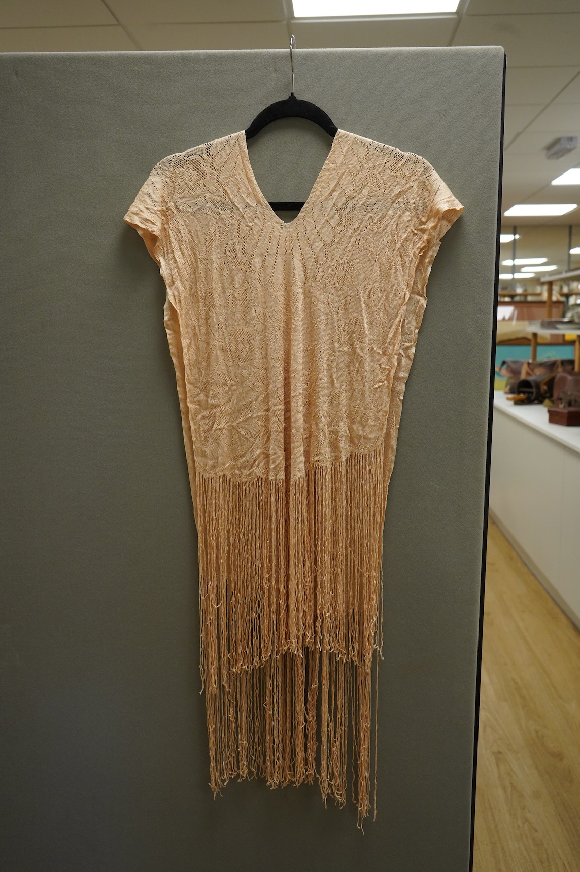 A 1920’s-30’s silk stockinette fringed ladies open sided knitted tabard, sides 56cm long not including fringe. Condition - front point of V slightly worn.